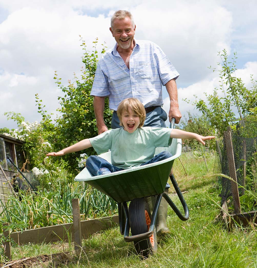 Opa und Enkel haben Spaß mit der Schubkarre im Garten